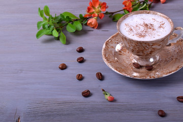 Freshly brewed coffee with milky foam topped with cinnamon in a cup against the gray wooden background