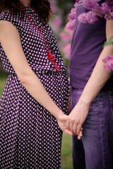 hands of husband and wife on background of pregnant woman belly holding hads.