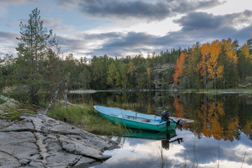 An evening landscape with a motor boat and the autumn forest.