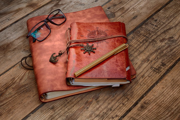 Vintage writing materials still life: two brown leather vintage notebooks or books, glasses and...
