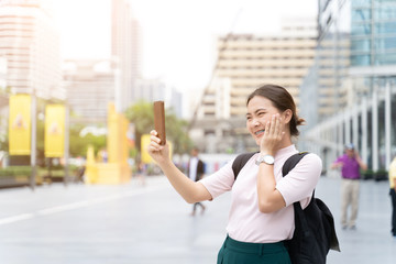 Happy asian woman taking a selfie in the city