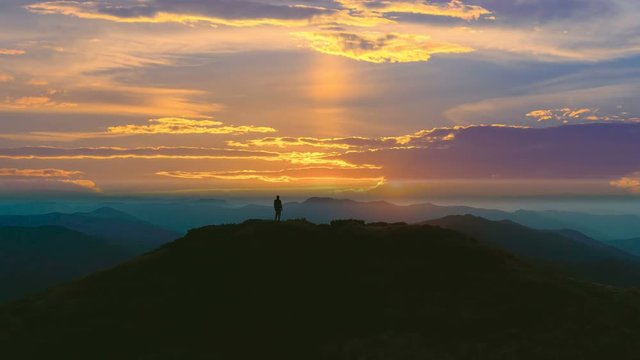 The man standing on the mountain against the beautiful sunrise. time lapse