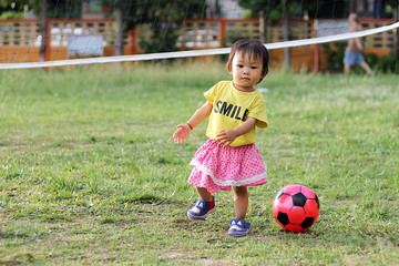 Happy Asian baby child girl practice to walking at the field with a ball toy. Baby aged of one year old.