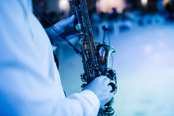 Fototapeta premium The musician plays the saxophone indoors close-up. The saxophonist plays the saxophone at the event close-up.
