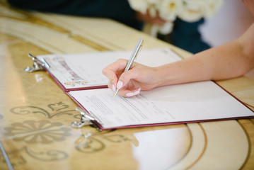 The bride signs on the registration in the document on the wedding day