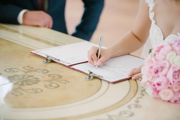 The bride signs on the registration in the document on the wedding day