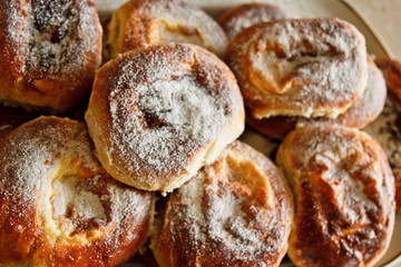 buns in plates full of freshly baked cheesecakes sprinkled with powdered sugar on the kitchen table. cooking baking. baking preparation stage. breakfast close up top view