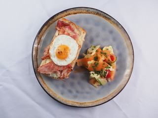 Sandwich with a fried egg, bacon, cheese and vegetables