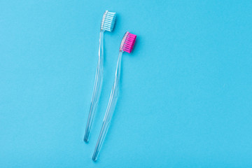 Two plastic colorful toothbrushes on a blue background, close up
