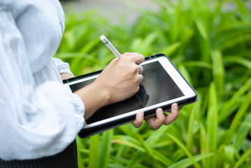Women read or analyze reports on tablet computers. In the midst of nature