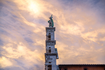 Statue on top of facade of Chiesa di San Michele in Foro St Michael Roman Catholic church in historical centre of old medieval town Lucca, evening view, cloudy dramatic sky background, Tuscany, Italy