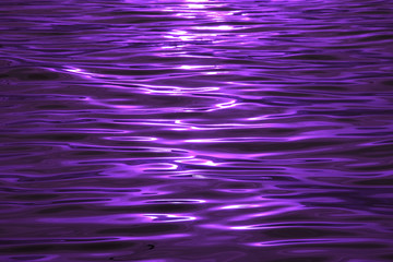 Sea ripples with sunlight reflections in purple color for background or banner