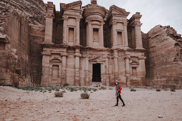 Woman standing in front of ancient temple in rock face in Al Khazneh, Petra, Jordan