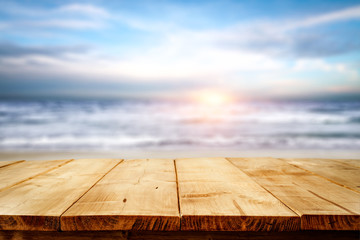 Wooden table with space for your product or object. A blurry landscape of the sea and the beach. A few days and a sunny light.