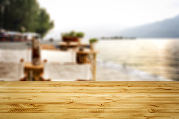 Wooden table with space for your product or object. A blurry landscape of the sea and the beach. A few days and a sunny light.