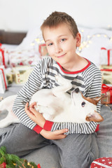 boy playing with dog jack russell on a bed with new year's decoration