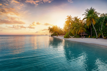 Obraz na płótnie Canvas Sonnenuntergang über einer einsamen, tropischen Insel mit Palmen und Hängematte am Strand