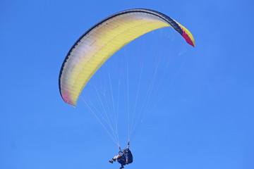 Tandem paraglider flying yellow wing