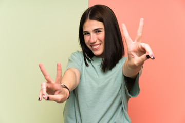 Young woman over isolated colorful wall smiling and showing victory sign
