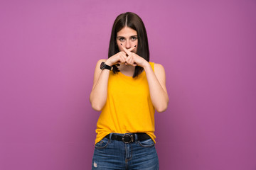 Young woman over isolated purple wall showing a sign of silence gesture