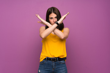 Young woman over isolated purple wall making NO gesture
