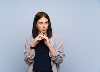 Young woman over isolated blue wall scheming something