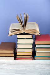 Open stacking book, hardback colorful books on wooden table and blue background. Back to school. Copy space for text. Education business concept.