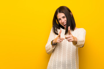Young woman over isolated yellow wall pointing to the front and smiling