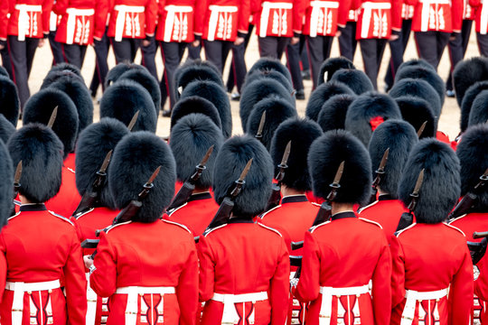 Close up of soldiers marching at the Trooping the Colour military parade at Horse Guards, London UK. Guards are wearing iconic black and red uniform and bearskin hats.