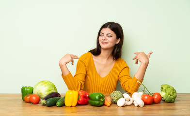 Fototapeta premium Teenager girl with many vegetables proud and self-satisfied