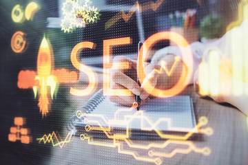 Multi exposure of woman's hands making notes with SEO icon. Concept of Search engine optimization