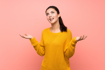 Teenager girl  over isolated pink wall making doubts gesture