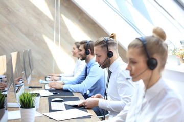 Portrait of call center worker accompanied by his team. Smiling customer support operator at work.