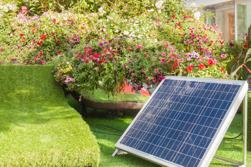 Solar panell in back or front house yard with trees and flowers warm sunny spring or summer day.