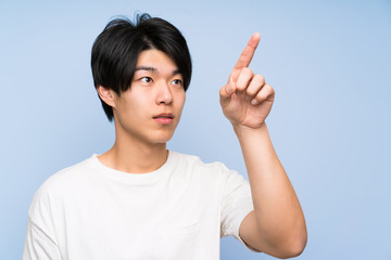 Asian man on isolated blue background touching on transparent screen