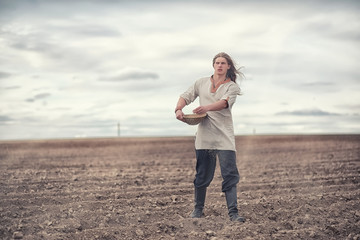 A young peasant sows the field with grain