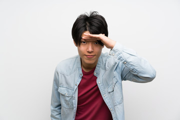 Asian man on isolated white background looking far away with hand to look something