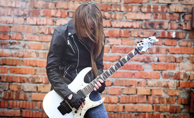 Beautiful young girl rocker with electric guitar. A rock musician girl in a leather jacket with a...