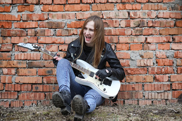  A rock musician girl in a leather jacket with a guitar