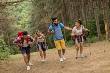 Happy young group hiking together through the forest