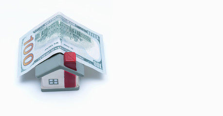 model of a new house is covered with a hundred dollar bill, a symbol of financial security and stability