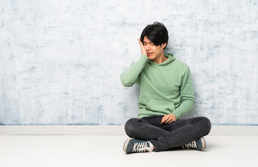 Asian man sitting on the floor with toothache