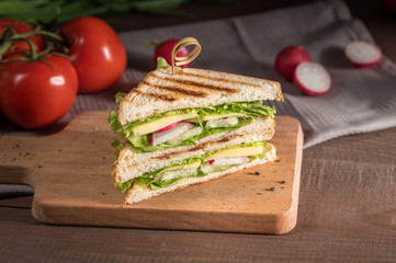 Club sandwich with vegetables on rustic background