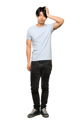 Fototapeta premium A full-length shot of a Asian man with blue shirt with an expression of frustration and not understanding over isolated white background