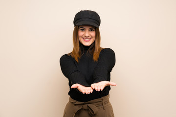 Fashion woman with hat holding copyspace imaginary on the palm to insert an ad