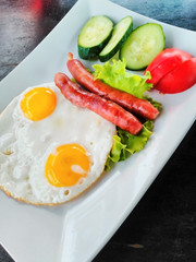 Morning breakfast with eggs sausages and vegetables