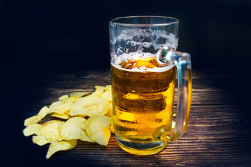 Just a glass of beer and chips on a vintage wooden table