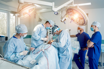 Spinal surgery. Group of surgeons in operating room with surgery equipment. Laminectomy