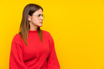 Fototapeta premium Young woman over isolated yellow wall standing and looking side