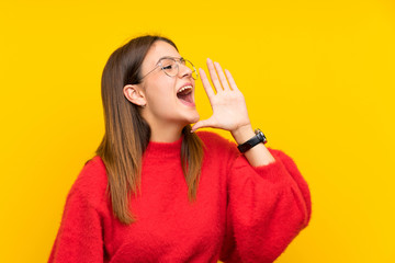 Young woman over isolated yellow wall shouting with mouth wide open